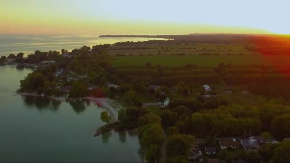 Birds fly through the frame over top of Selkirk. Aerial shot showing Lake Erie, Ontario, Canada. alt