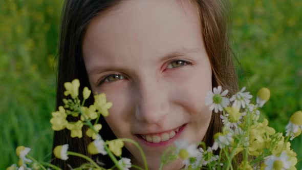 Portrait of Happy Smiling School Age Girl Holding Wildflowers Looking at Camera