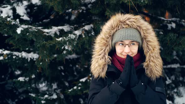Young Happy Woman in a Romantic Mood Warms Her Hands While Walking in the Winter Forest