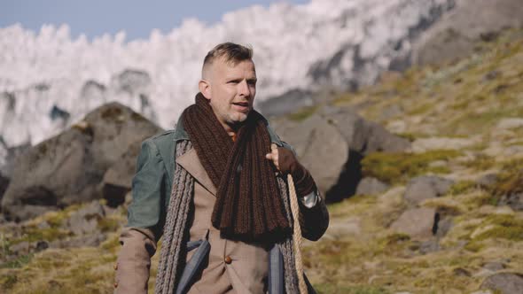 Man In Greatcoat Carrying Guitar Case And Bag Down Hill alt