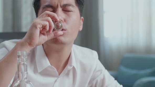Close Up Of Drunk Asian Man Pours Vodka In A Shot Glass And Cheers Before Drinking At Home alt