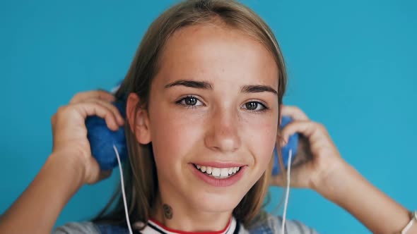 Teenage Girl Putting on the Headphones Listening to Music and Dancing alt