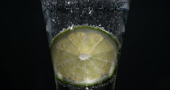 Slice of Green Lemon, citrus aurantifolia, in a Glass, Real Time 4K