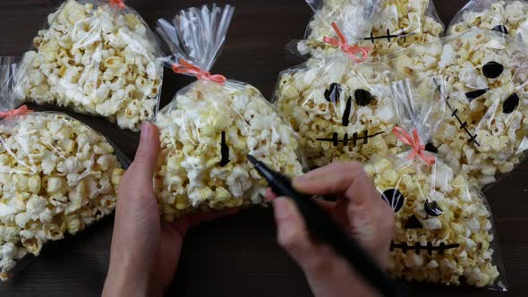 Process of making goodies for Halloween party. Drawing a skull on the plastic bag with popcorn