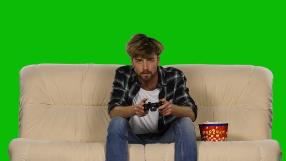 Gamer Is Playing with a Joystick While Eating Popcorn. Green Screen alt