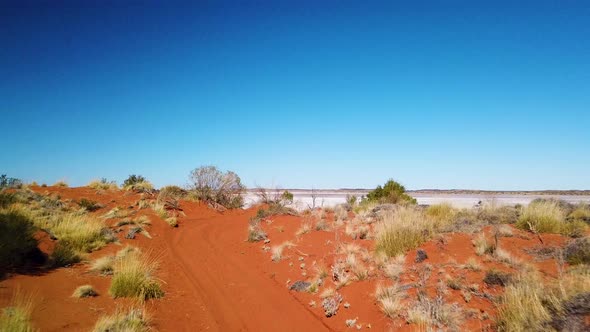 Drone reveals huge dry salt lake after flying up over remote red dirt trail in Australian outback. alt