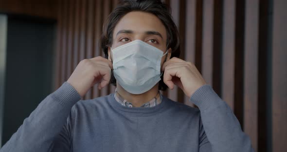 Slow Motion Portrait of Arab Guy Taking Off Medical Face Mask and Breathing Hard Indoors alt