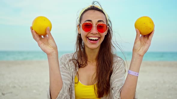 Funny Playful Young Woman Wearing Summer Clothes Holding Fruits Over Her Eyes alt