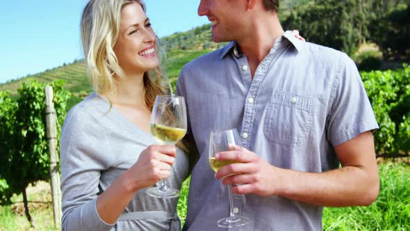 Woman kissing man while toasting wine in vineyard alt