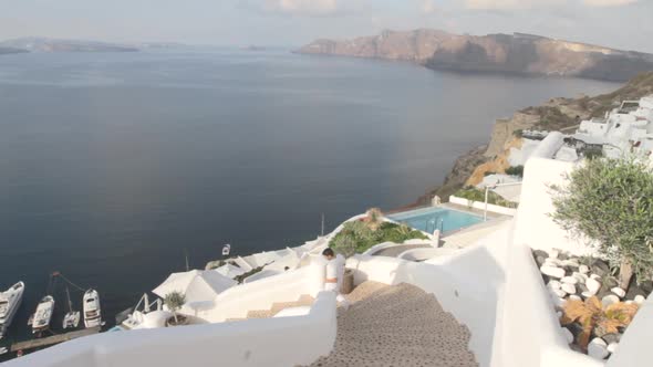 A man is rushing down some open air stairs in a village alley at the Greek village of Oia in Santori alt