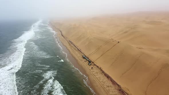up down aerial shot of cars on a beach at the edge of the Namibia desert alt