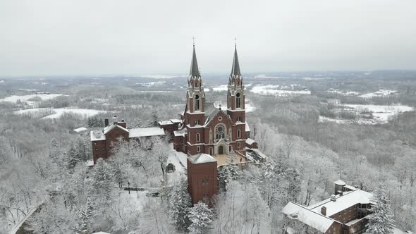 Drone view of religious complex in winter. Forest trees covered in snow.