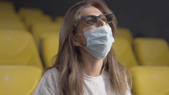 Close-up of Young Beautiful Brunette Woman in Face Mask Putting on 3d Glasses in Cinema alt