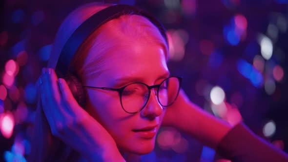 Young Female Dj in Headphones and Glasses Dances to Energetic Music in the Club