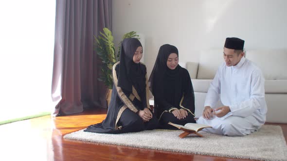 Handsome Muslim man explaining two young women read Quran 