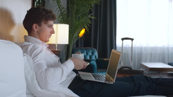 Businessman Drinking Coffee and Using Laptop in Hotel alt
