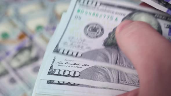 A man's hands are counting a stack of one hundred dollar bills alt