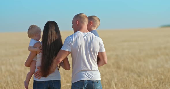 Young Father Walks with His Family in a Wheat Field alt