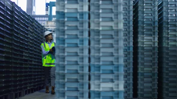 Female Storehouse Employee Inspecting Blue Supply Crates Checking Delivery alt