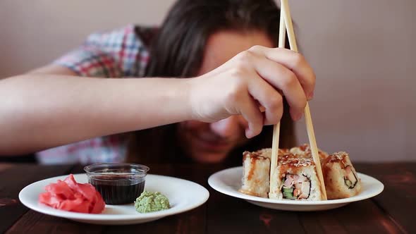 A Woman Eats Rolls Takes Them with Chopsticks Lies Down