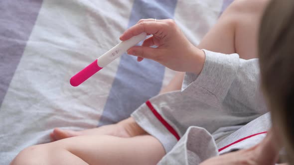 Woman in Bed with Positive Pregnancy Test
