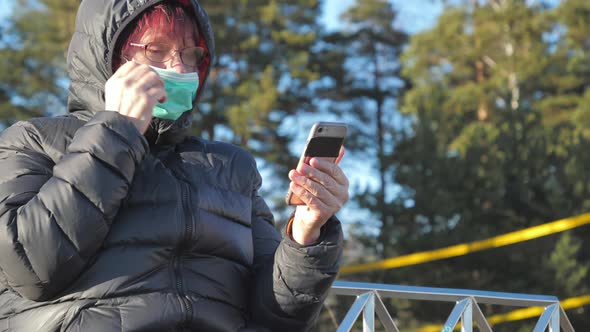 A Lady in Her Face Mask Checking Her Phone in Finland