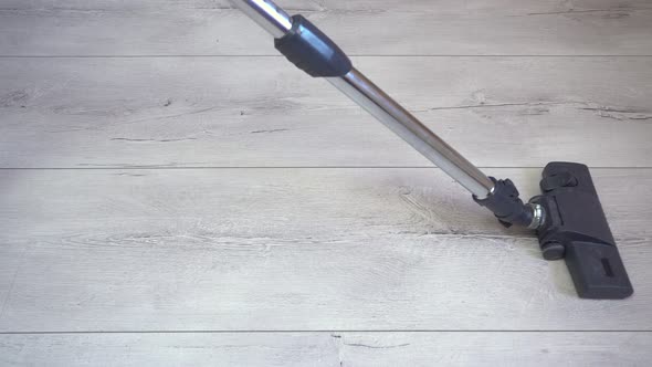 The Vacuum Cleaner's Brush Sucks in Dust on the Gray Laminated Surface alt