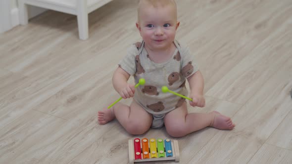 Cute Little Child Sitting on the Floor Playing with Colorful Wooden Xylophone Musical Toy for Kids alt