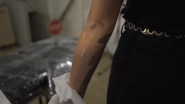 Crop tattoo master shaving arm of client alt