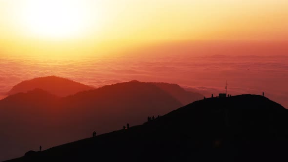 Boundless Mountains with Fog and Hiker Silhouettes at Sunset