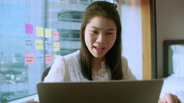attractive asian adult feMale businesswoman freelancer working at home behind a laptop