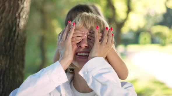 Closeup Portrait of Excited Woman Laughing As Little Girl Covering Eyes with Hands alt