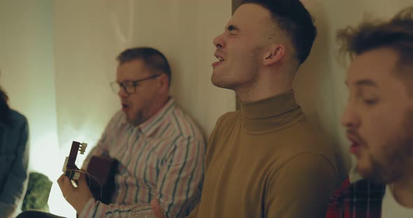 Cute Men Emotionally Sing a Song with a Guitar in a Cozy Atmosphere alt