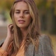 Close-up Portrait of Beautiful Caucasian Woman Standing in Autumn Park and Tucking Hair