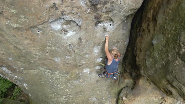 Determined Senior Woman Climber Clambering Up Steep Wall of Rocky Mountain alt