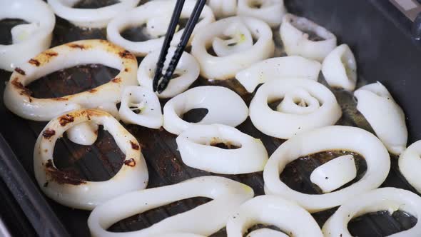 Cooking squid rings in a frying pan. Rings of calamari are frying in grill pan in kitchen alt