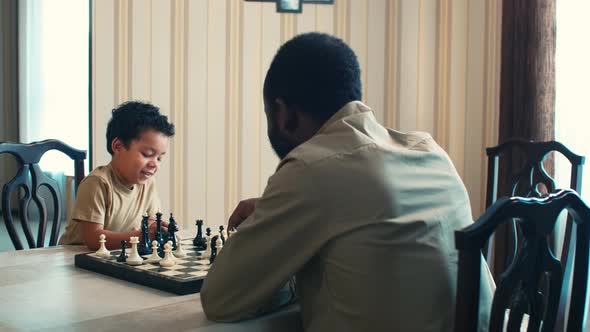 Son studying to play checkmate with father at home