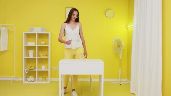 Young Woman Comes Into Shot and Pours Milk In Glass alt