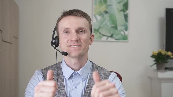 Young Businessman Communicates By Video Link Smiles and Raises His Thumbs Up alt