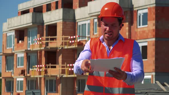 Angry Construction Worker Holds Some Papers, Throws Them Away and Talks To Camera alt