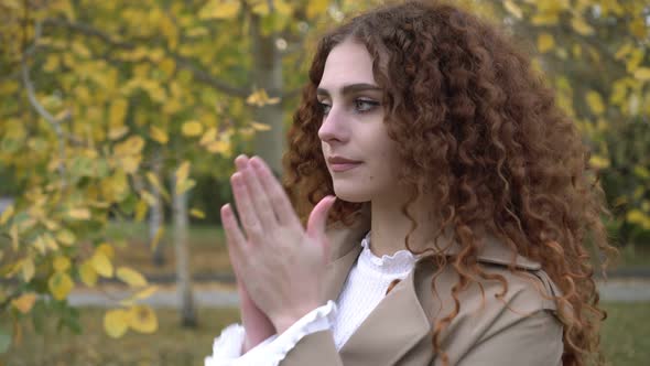 A Young Woman Freezes on the Street Against a Background of Yellow Foliage alt