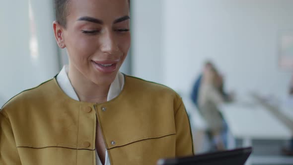 Young short hair business woman standing in the office and using digital tablet in front of her team