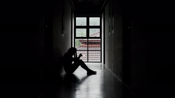 Lonely young man feeling depressed and stressed sitting in the dark walkway alt