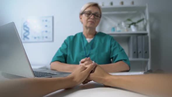 Aged Physician Listening to Nervous Female at Exam Touching Hands and Comforting