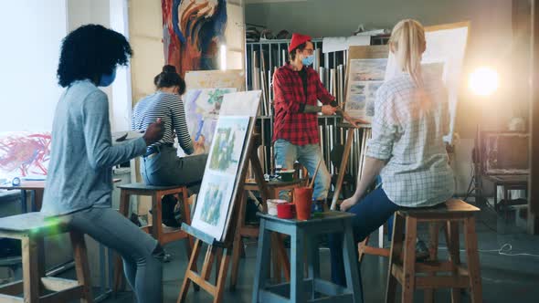 A Man in a Face Mask is Teaching Painting in the Studio alt