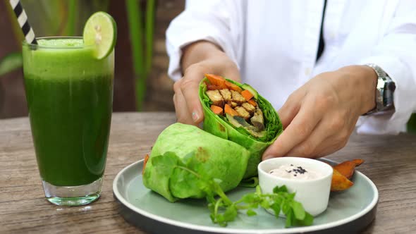 Eating Clean Person Shows to the Camera Plant Based Wrap Cut in a Half Full of Greens Vegetables and alt