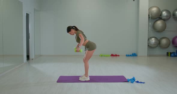 Sports Girl Performs Dumbbell Swings to the Side