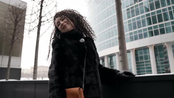 a Curlyhaired Middleaged Woman a Brunette in a Black Fur Coat Walking Alone in the City on a Cold alt