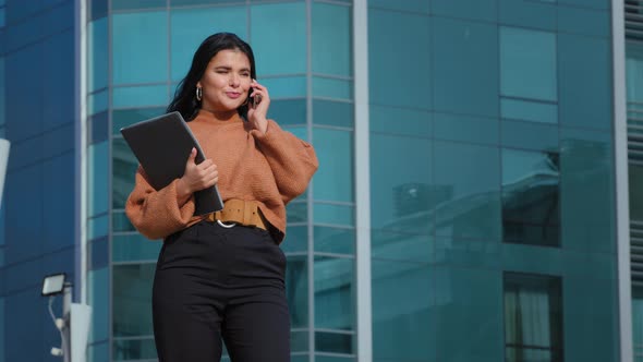 Happy Businesswoman Stands on Background Office Building Speaks on Mobile Phone Answers Friendly alt