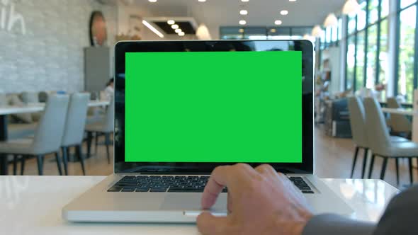 Man hand working in office interior onlaptop computer with chroma key green screen